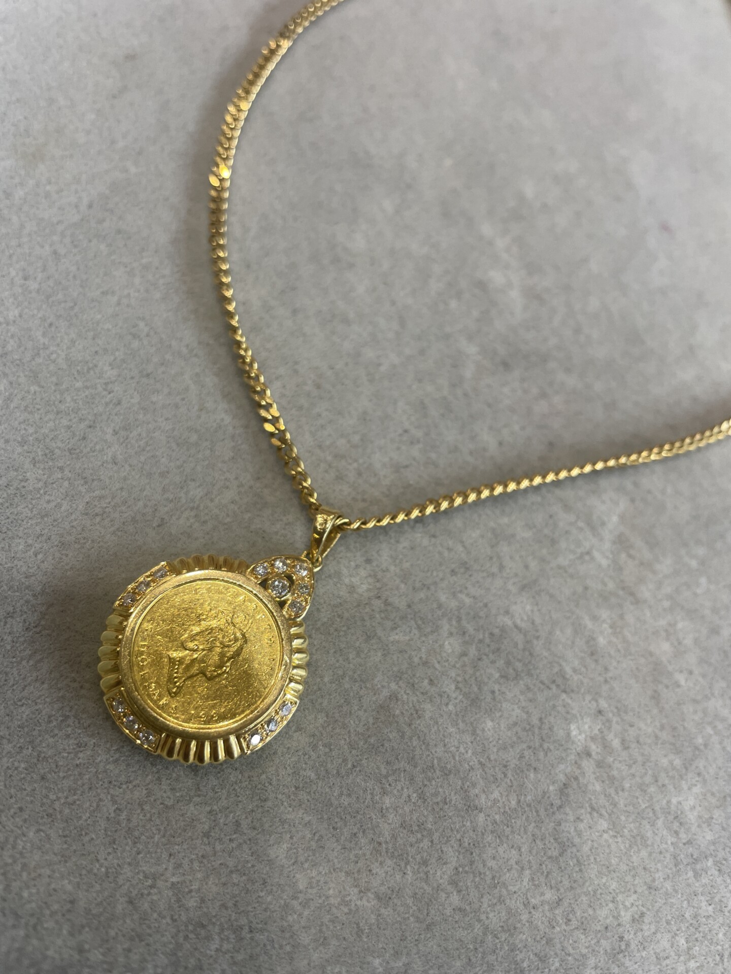 A necklace with a pure gold coin and an 18-karat gold pendant.